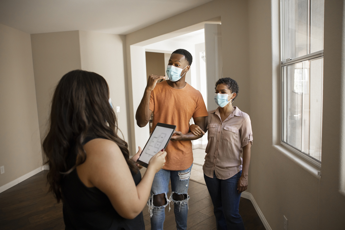 Couple speaking to real estate agent while wearing masks